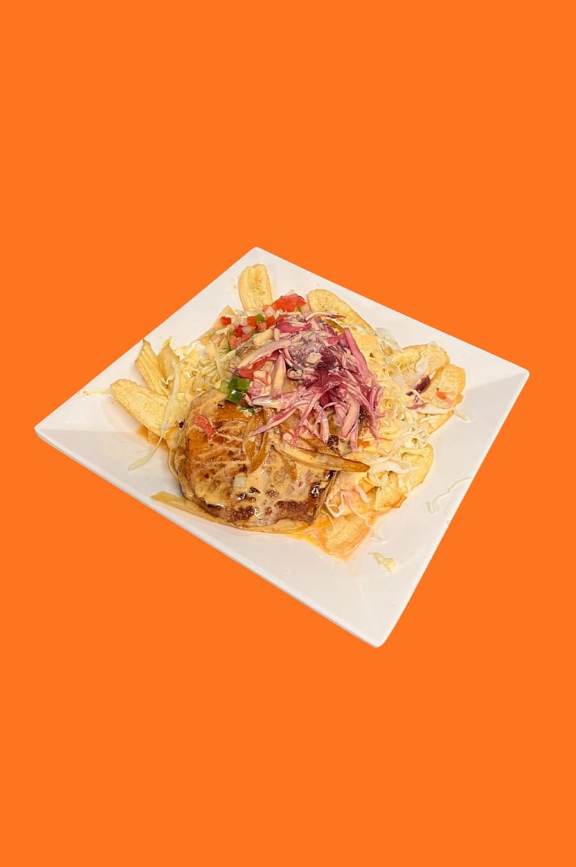 Honduran dish with fried plantains, meat, cabbage, and red onion on a white plate.